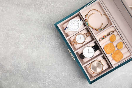 Elegant jewelry box with beautiful bijouterie and expensive wristwatches on light gray stone table, top view. Space for textの写真素材