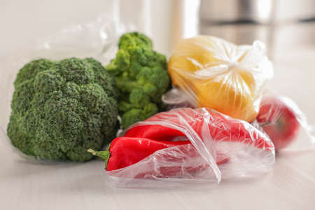 Plastic bags and fresh products on white table, closeupの写真素材