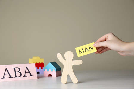 Woman holding paper with word Man near human figure and abbreviation ABA (Applied behavior analysis)...