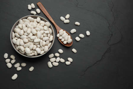 Raw white beans on black table, flat lay. Space for text