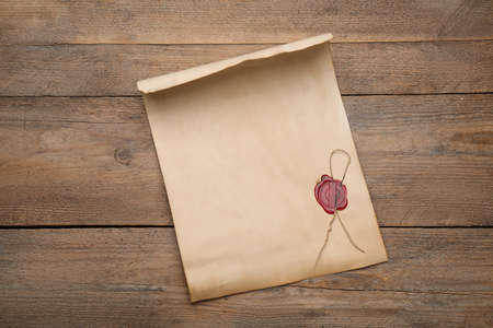 Sheet of old parchment paper with wax stamp on wooden table, top view. space for designの写真素材