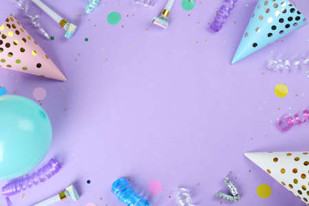 Frame of colorful serpentine streamers and other party accessories on violet background, flat lay....