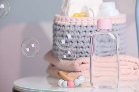 Bottle of baby cosmetic product, wooden toy and accessories on white table against color background. Space for textの写真素材