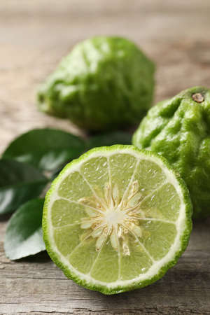 Fresh ripe bergamot fruits with green leaves on wooden table, closeupの写真素材