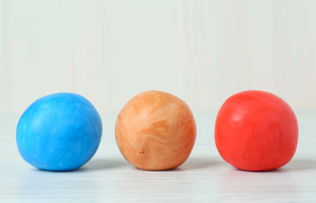Different color play dough balls on white wooden table, closeupの写真素材