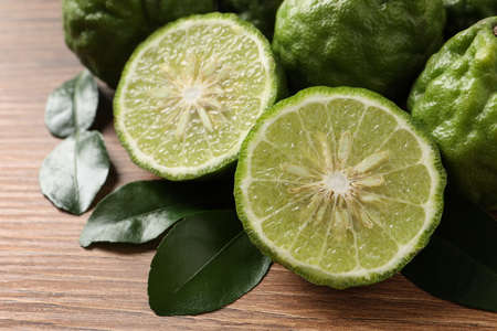 Fresh ripe bergamot fruits with green leaves on wooden table, closeupの写真素材