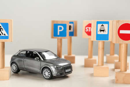 Miniature road signs and car on white table. driving school