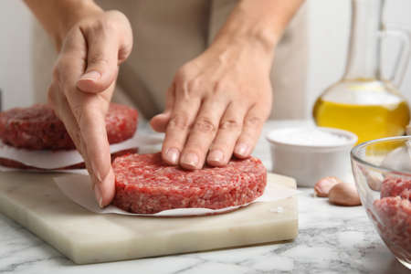 Woman making hamburger patties at white marble table, closeupの写真素材