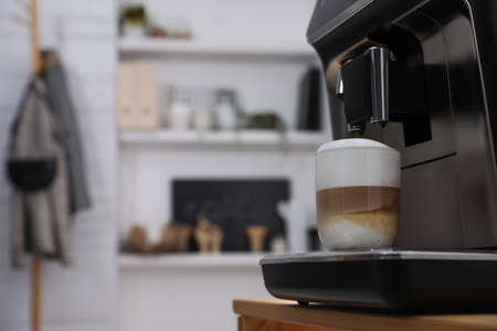 Modern coffee machine with cup of latte in office kitchen, space for textの写真素材