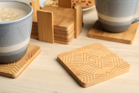 Stylish wooden cup coasters and mugs on tableの写真素材