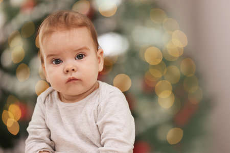 Cute little baby against blurred festive lights, space for text. Winter holidayの写真素材