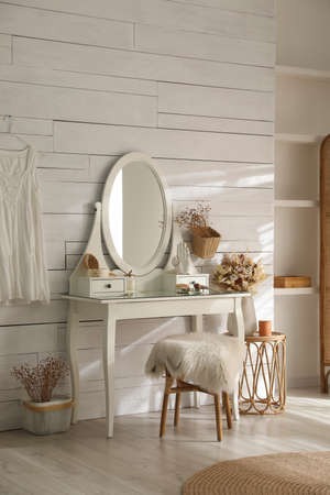 Wooden dressing table with decorative elements and makeup products in the room. interior design