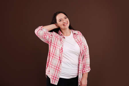 Beautiful overweight woman with charming smile on brown background
