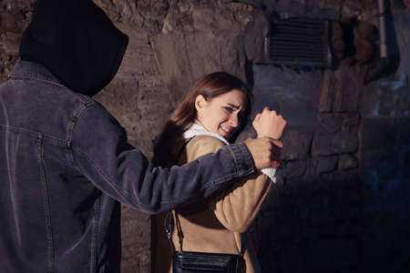 Criminal attacking young woman in alley at night. self defense conceptの写真素材
