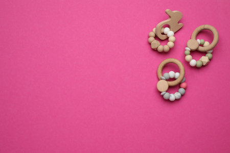 Cute wooden baby toys on bright pink background, flat lay. Space for textの写真素材