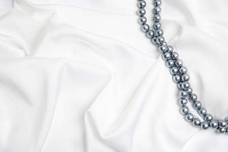 Beautiful pearls on white silk, top view. Space for textの写真素材