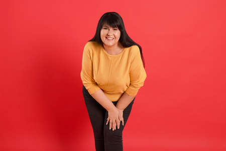 Beautiful overweight mature woman with charming smile on red background