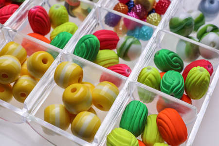 Plastic organizer with different beads on white background, closeup