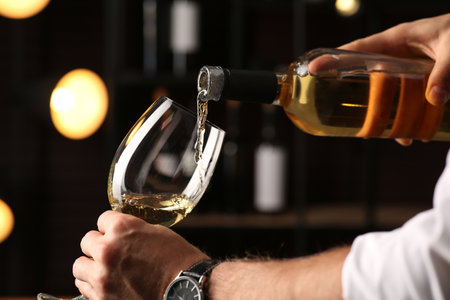 Man pouring white wine into glass indoors, closeupの写真素材