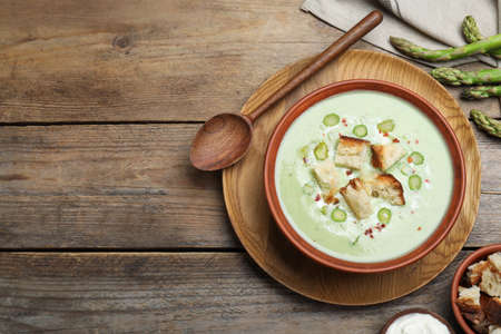 Delicious asparagus soup with croutons served on wooden table, flat lay. Space for textの写真素材