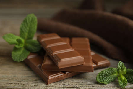 Tasty milk chocolate pieces with mint on wooden table, closeupの写真素材