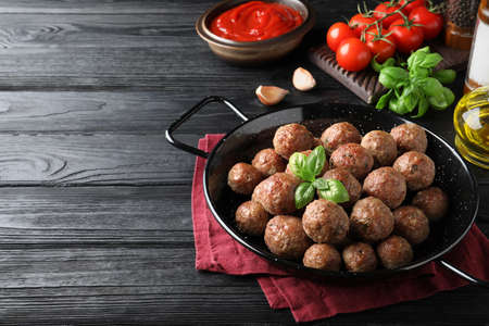 Tasty cooked meatballs with basil on black wooden table. Space for textの写真素材