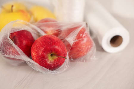 Plastic bag with fresh apples on white table, closeupの写真素材