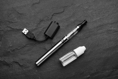 Electronic smoking device, charger and vaping liquid on black background, flat layの写真素材