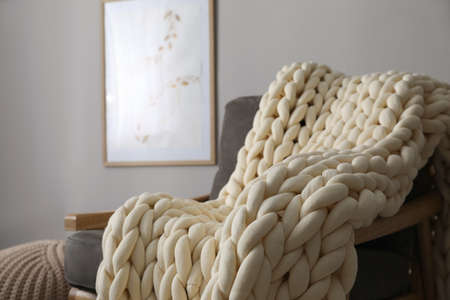 Soft chunky knit blanket on armchair in room