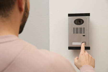 Man ringing intercom with camera in entrywayの写真素材