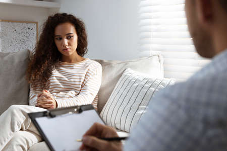 Unhappy African American woman having session with her therapist indoorsの写真素材