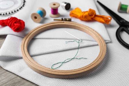Embroidery hoop, fabric and other accessories on wooden table