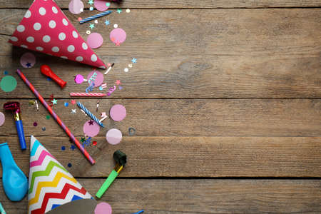 Colorful party hats and other festive items on wooden table, flat lay. Space for textの写真素材