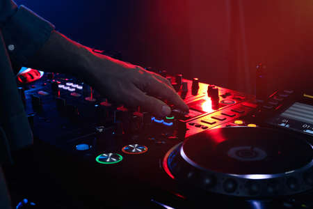 DJ creating music on modern console mixer in night club, closeup
