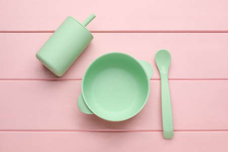 Set of plastic dishware on pink wooden background, flat lay. Serving baby foodの写真素材