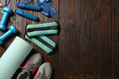Turquoise weighting agents and sport equipment on wooden table, flat lay. Space for textの写真素材