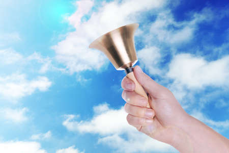 Woman with school bell against blue sky, closeupの写真素材