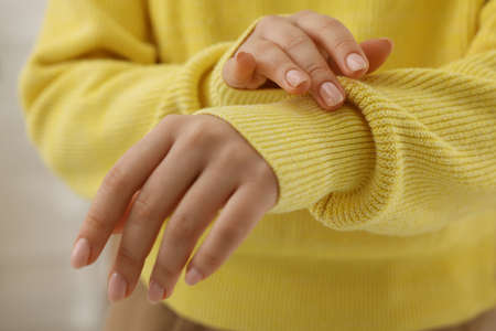 Woman touching sweater made of soft yellow fabric, closeup