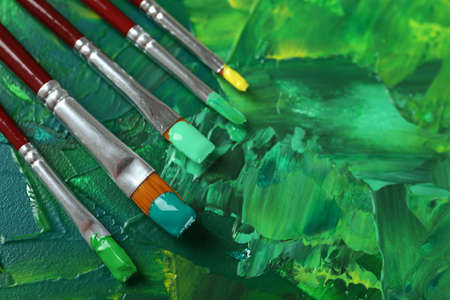 Set of different brushes on abstract colorful paint, closeupの写真素材