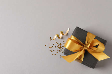 Beautifully wrapped gift box and confetti on gray background, flat lay. Space for text