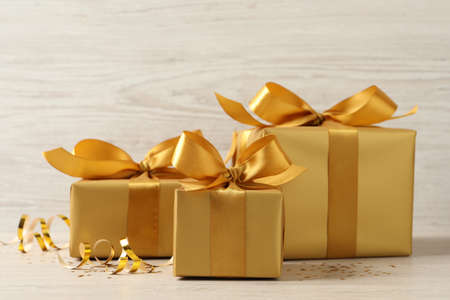 Beautifully wrapped gift boxes and confetti on white wooden table