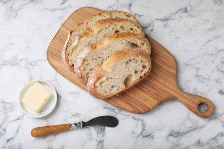 Freshly baked soda water bread and butter on white marble table, flat lay