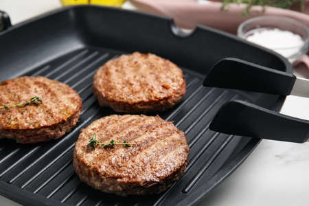 Grill pan with tasty fried hamburger patties on white tableの写真素材