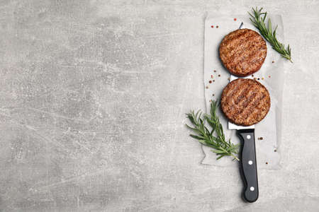 Tasty grilled hamburger patties, knife and seasonings on gray table, flat lay. Space for textの写真素材