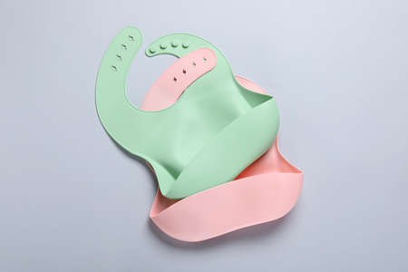Color silicone baby bibs on white background, top view