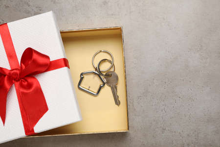 Key with trinket in shape of house on gray table, top view and space for text. house warming partyの写真素材