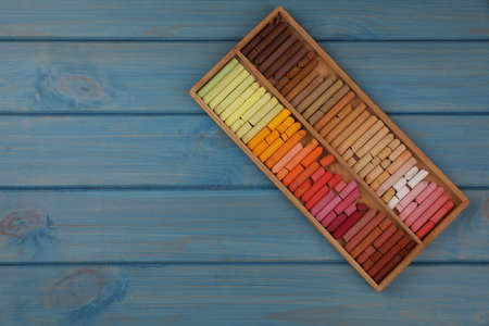 Drawing pastel set in box on light blue wooden background, top view. Space for textの写真素材