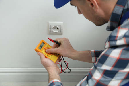 Electrician with tester checking voltage indoors, closeupの写真素材