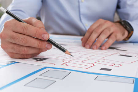 Professional cartographer working with cadastral map at table, closeup