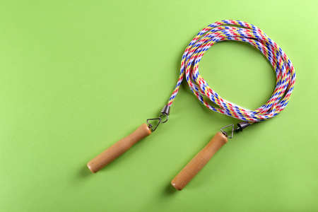 Skipping rope on green background, top view. Space for text
